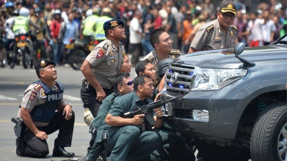 Indonesian police take position behind a vehicle as they pursue suspects after a series of blasts hit the Indonesia capital Jakarta on January 14, 2016.