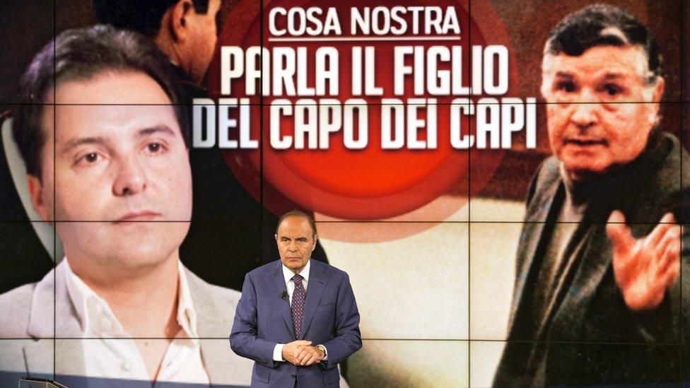 Italian TV host Bruno Vespa with a background showing Toto Riina and his son