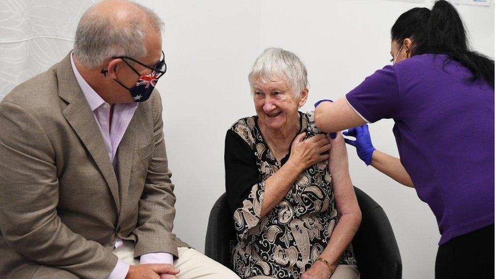 Woman receiving vaccine jab sitting next to Scott Morrison