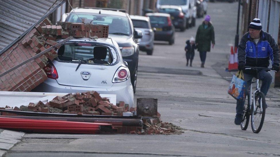 A brick wall falls on a car in the storm