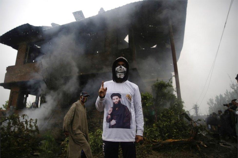 A Kashmiri youth wearing a shirt depicting a picture of militant commander Zakir Musa, as he stands inside of a damaged house where Musa was killed at Dadsara village in Tral, south of Srinagar, the summer capital of Indian Kashmir, 24 May 2019.