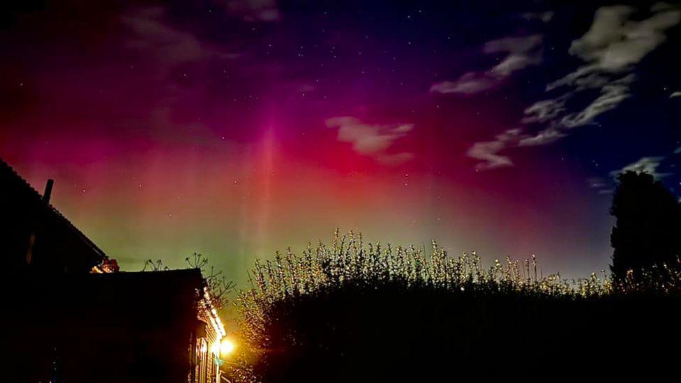 A house in the foreground in Winteringham with the Northern Lights above a hedge