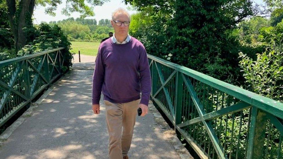 David Tarbet walking across a pedestrian bridge