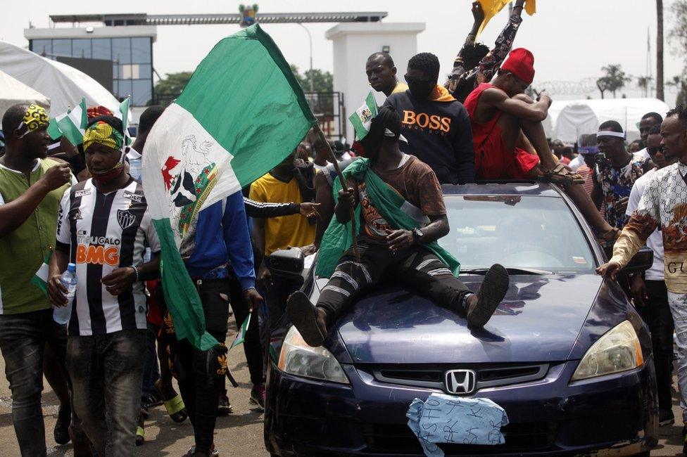 Protestors sit atop a car