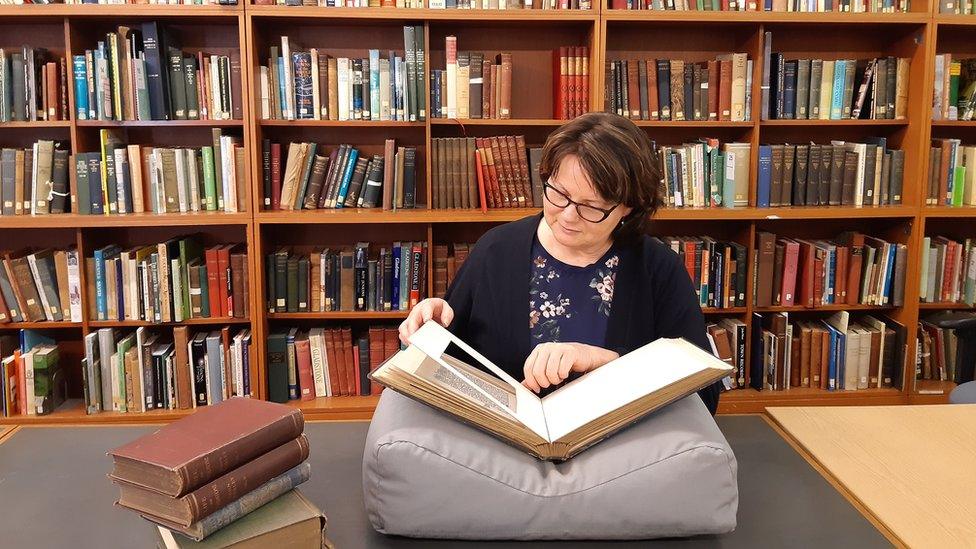 Bridget Thomas in the records office with a book