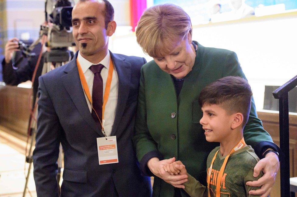 German Chancellor Angela Merkel stands with Afghan refugee boy Edris and his father at a Christian Democratic Union (CDU) party in Heidelberg (28 Nov)