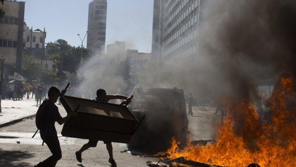 Demonstrators set a road block on fire outside the state legislature in Rio de Janeiro, Brazil, 6 December