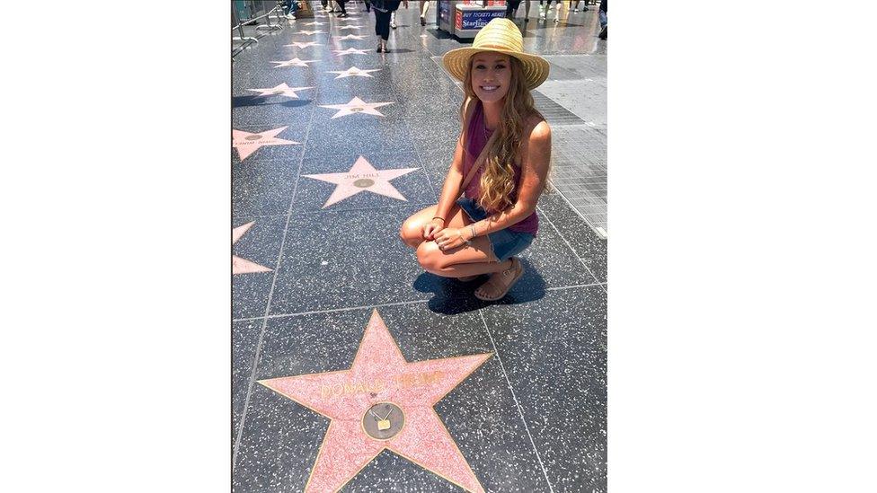 Makenna Greenwald kneels on Donald Trump star