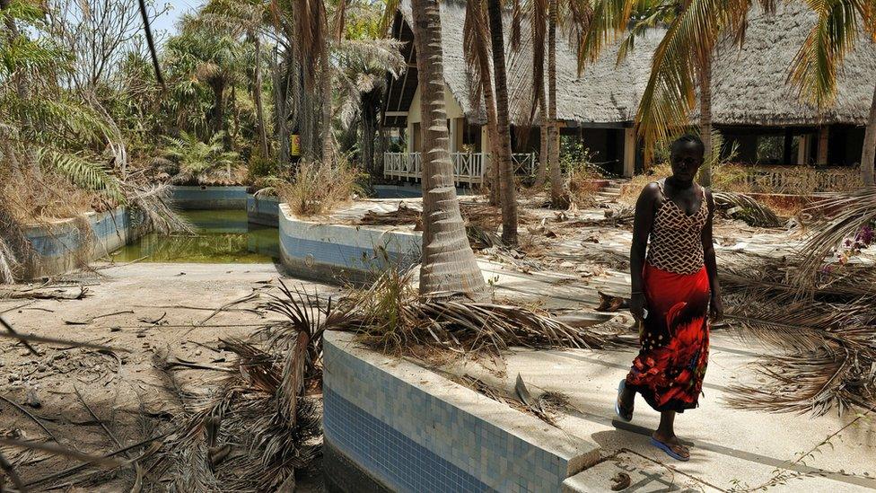 A Senegalese woman walks near an abandoned hotel