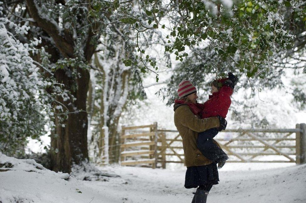 A woman holds her child whilst in the snow at Box Hill