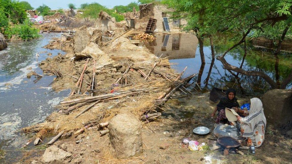 Flood affected women make bread for their family beside damaged mud houses after heavy monsoon rains in Jaffarabad district, Balochistan province, on August 28, 2022.