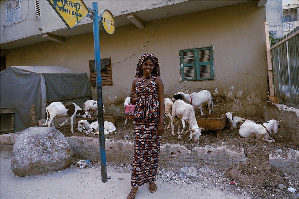 Twenty-two-year-old Rokhaya waits at a bus stop in her new outfit