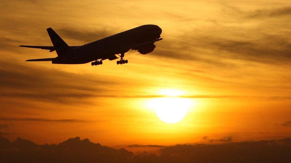 Plane taking off with sunset in background