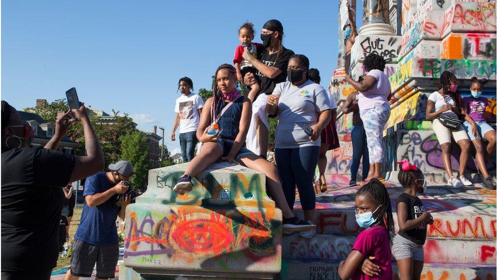 People visit the graffiti-covered statue of Confederate General Robert E Lee at Monument Avenue in Richmond, Virginia