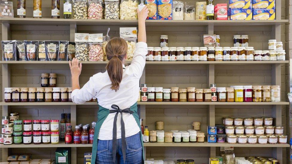 Shop worker places items on shelf