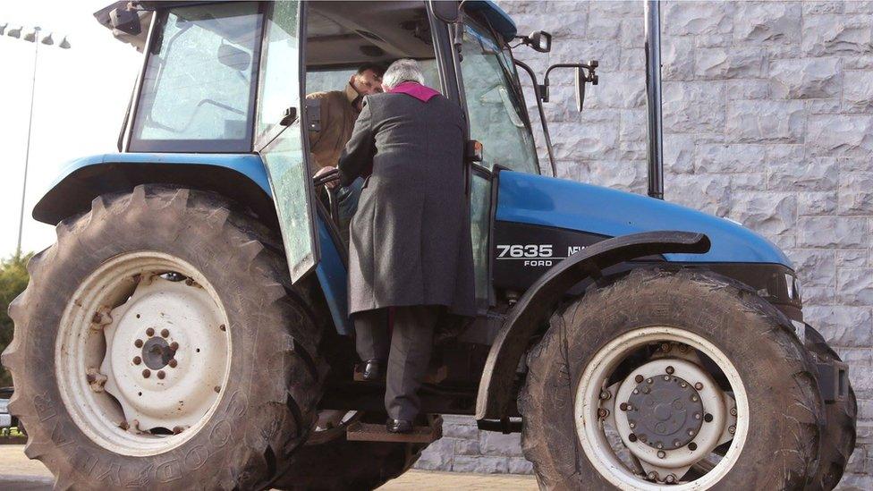 A farmer gets the traditional Ash Wednesday blessing from the comfort of his tractor