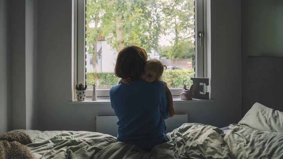 Mother and child sit on bed