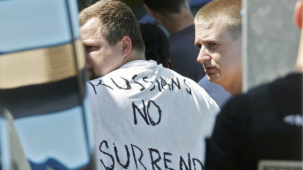 Russian soccer fans suspected of being involved in clashes, one wearing a banner saying "Russia No Surrender", are ushered off their bus