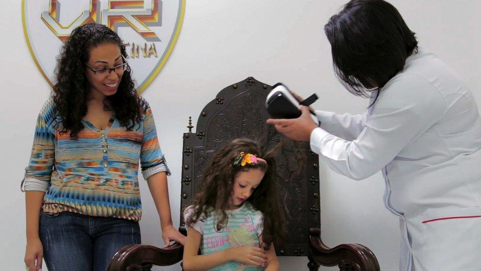 Nurse taking off VR headset from young girl while mother looks on