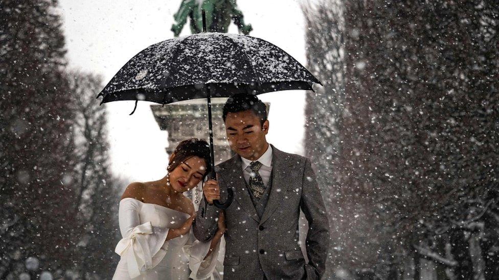 A newly wed couple poses during a photoshoot as snow falls over Paris on 22 January 2019