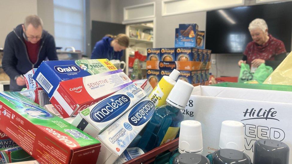 Toiletries on a table with volunteers packing them