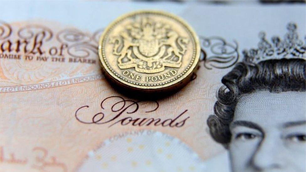 A pound coin resting on a Scottish ten pound note.