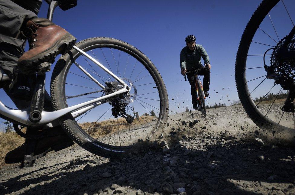 Low view of bicycle tyres with man in bike coming into view behind