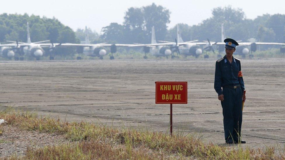 Vietnamese soldier stands next to a hazardous warning sign by a runway at Bien Hoa air base