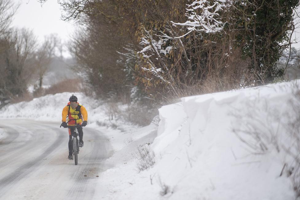 A cyclist makes their way through snow in Barham, near Ipswich, on 8 February 2021