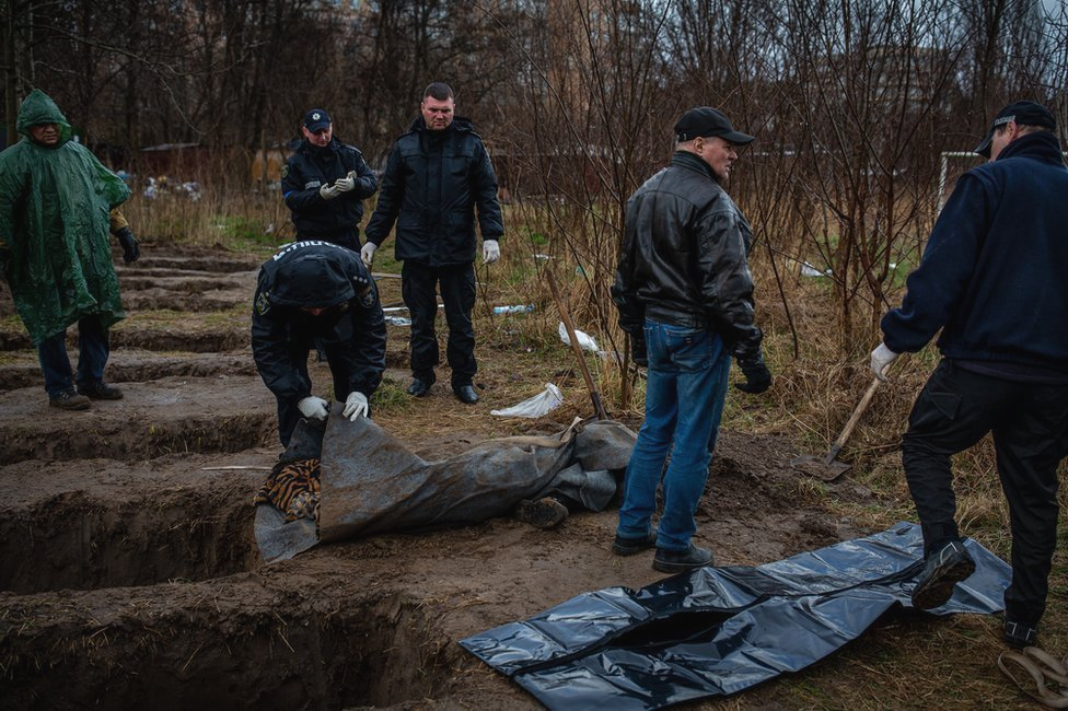 Nine graves, dug by neighbours behind apartment buildings in Bucha.