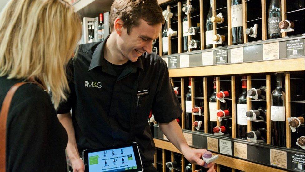 An M&S employee helping a customer choose wine