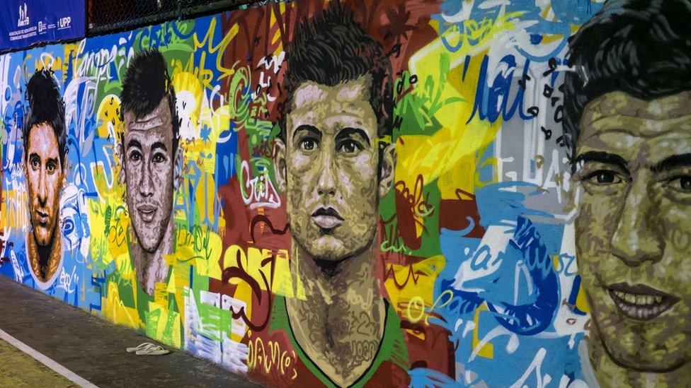 View of a mural with the portraits of famous football players at Tavares Bastos shanty town (favela) in Rio de Janeiro, Brazil, on May 21, 2014. Players are from left to right: Lionel Messi (Argentina), Neymar (of Brazil), Cristiano Ronaldo (of Portugal), Luis Suarez (of Uruguay).