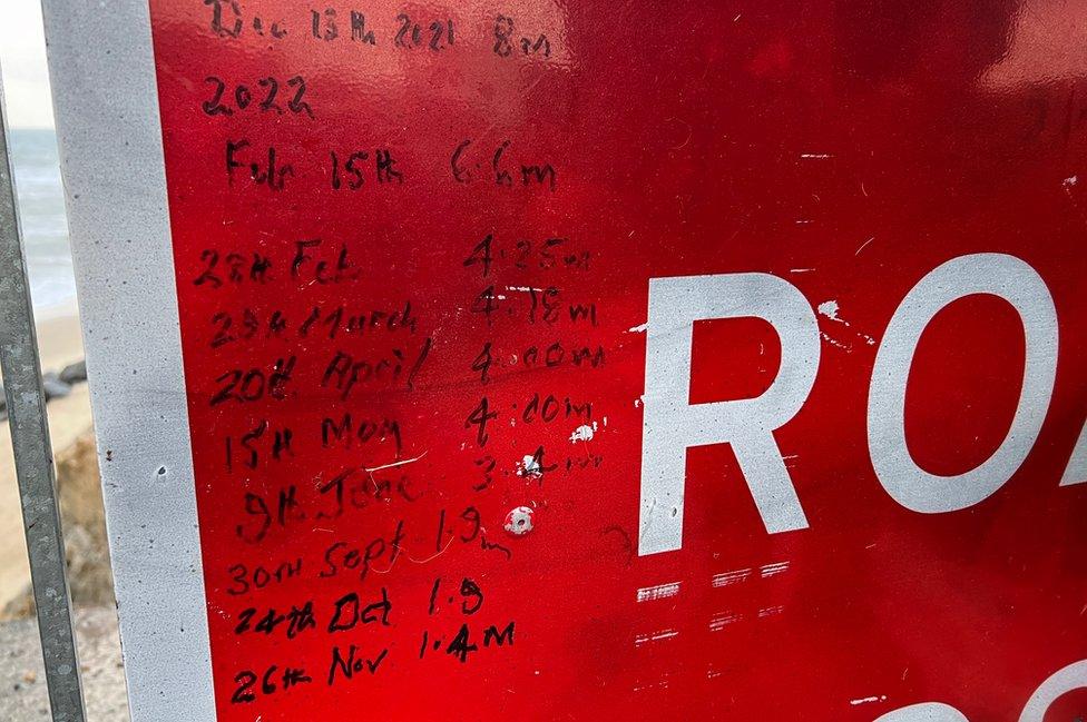 Road sign close up with figures showing how far away the sea is