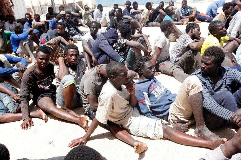 Migrants sit at a naval base after they were rescued by the Libyan coastguard in the coastal city of Tripoli, Libya