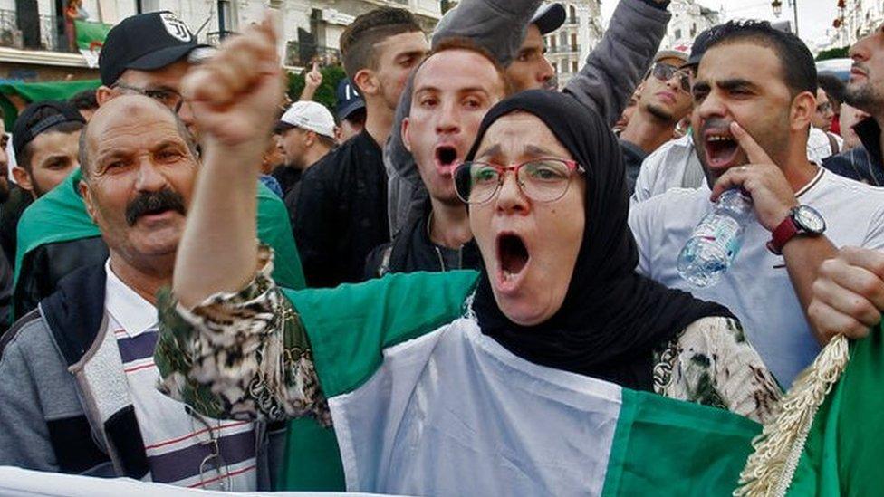 A crowd of people chanting and holding up banners