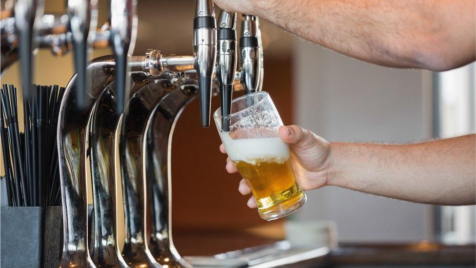 A barman pours a pint of beer in a bar