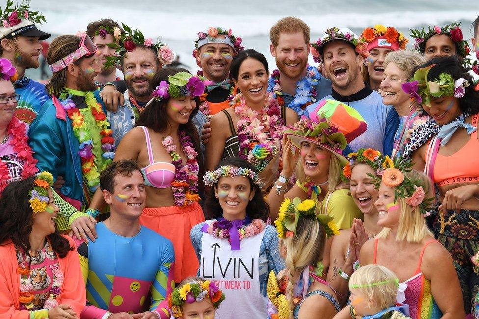 Prince Harry and Meghan, the Duchess of Sussex, pose with a local surfing community group at Bondi Beach in Sydney