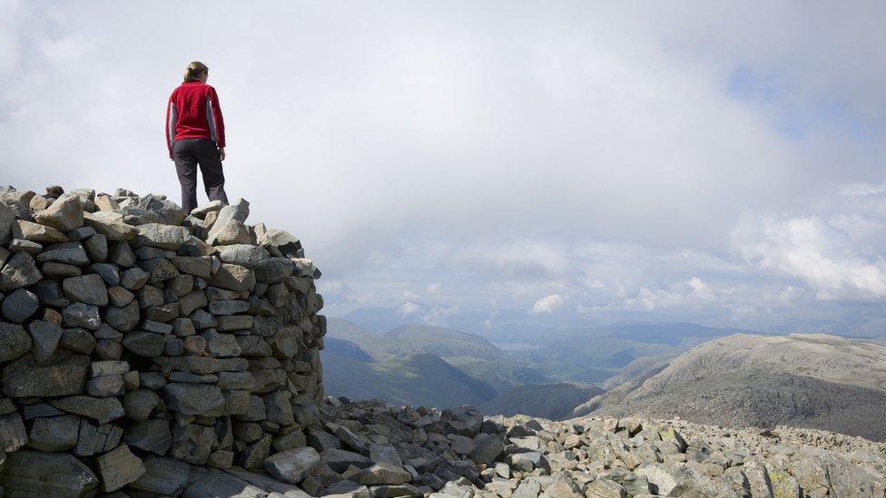 Walker at summit cairn of Scafell Pike