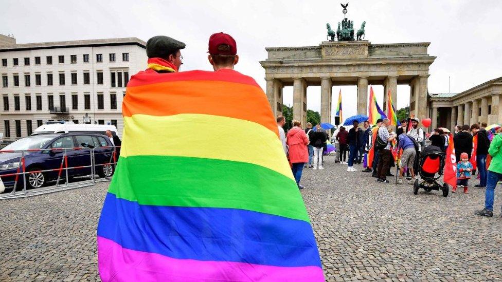 People wrapped in gay pride flag at the Brandenburg Gate, Berlin, Germany