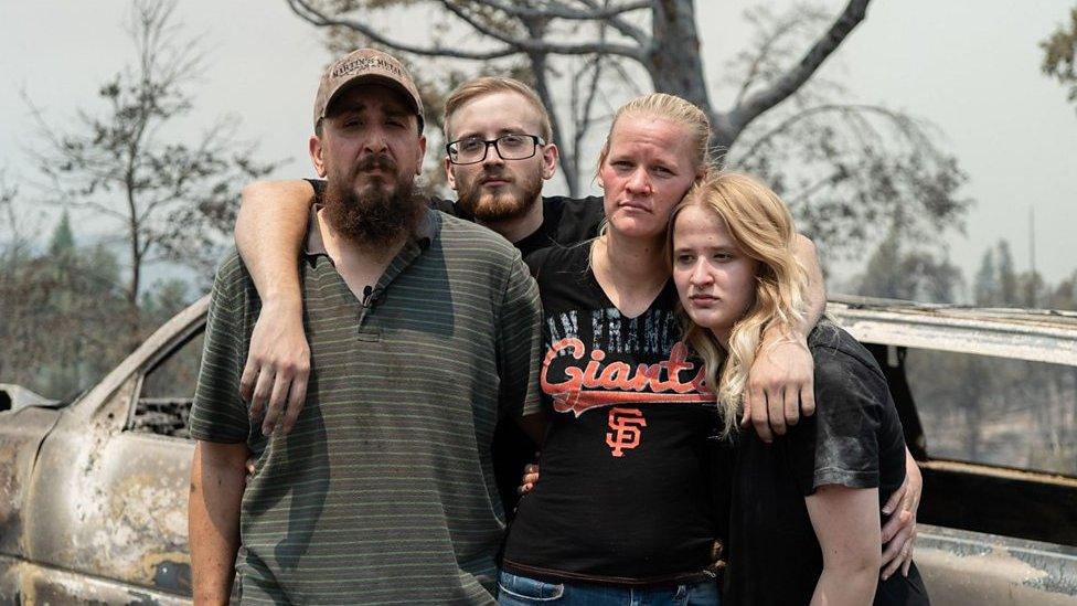 Family stands in remains of burned home