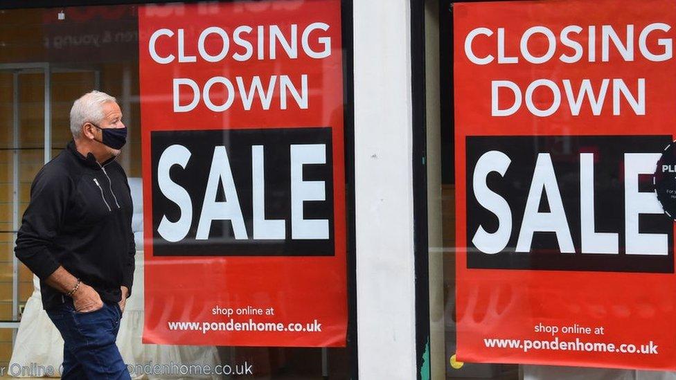 Man walking past a shop that is closing down