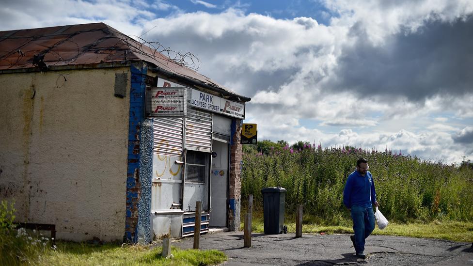 Man walks beside abandoned shop