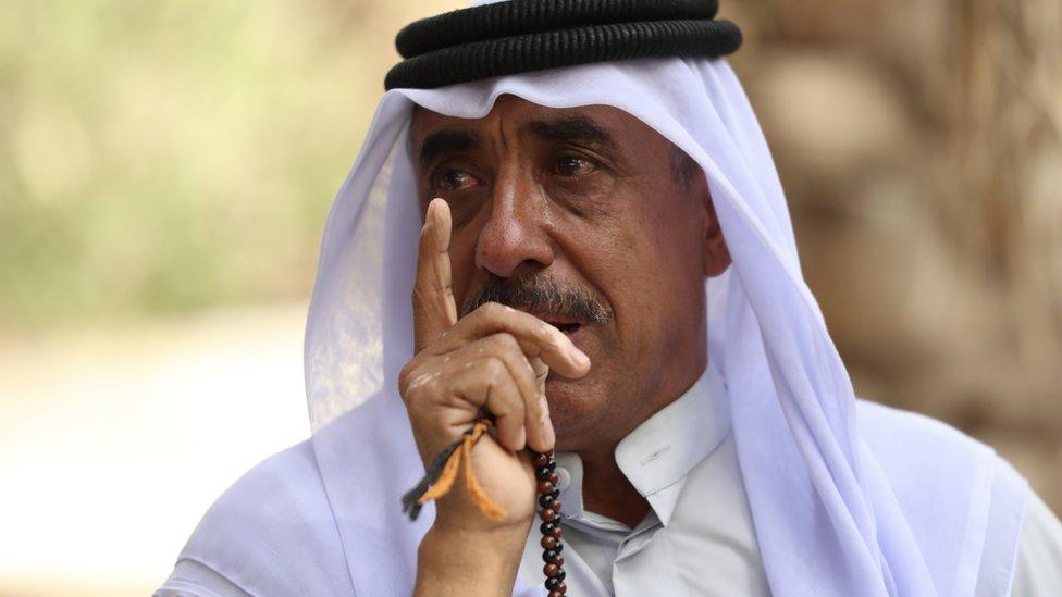 Hussein Julood sits in his home town of Rumaila carrying prayer beads