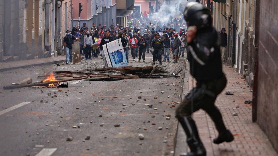 A riot police officer confronts demonstrators during clashes in Quito on 07 October, 2019