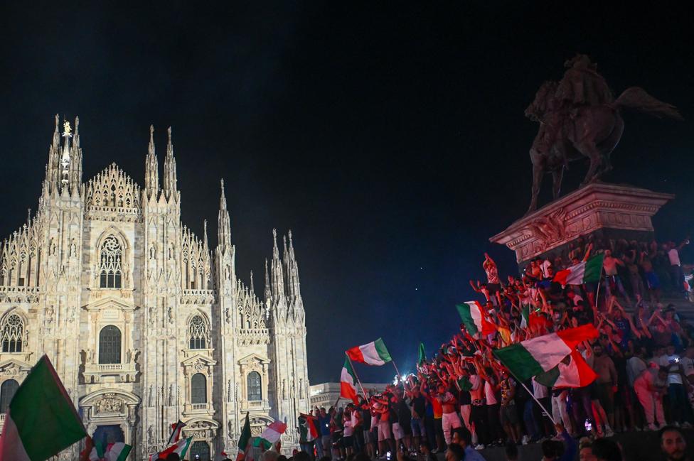 Supporters of the Italian national football team celebrate after Italy beat England 3-2 on penalties to win the UEFA EURO 2020 final football match between England and Italy in Piazza del Duomo in Milan on July 11, 2021.