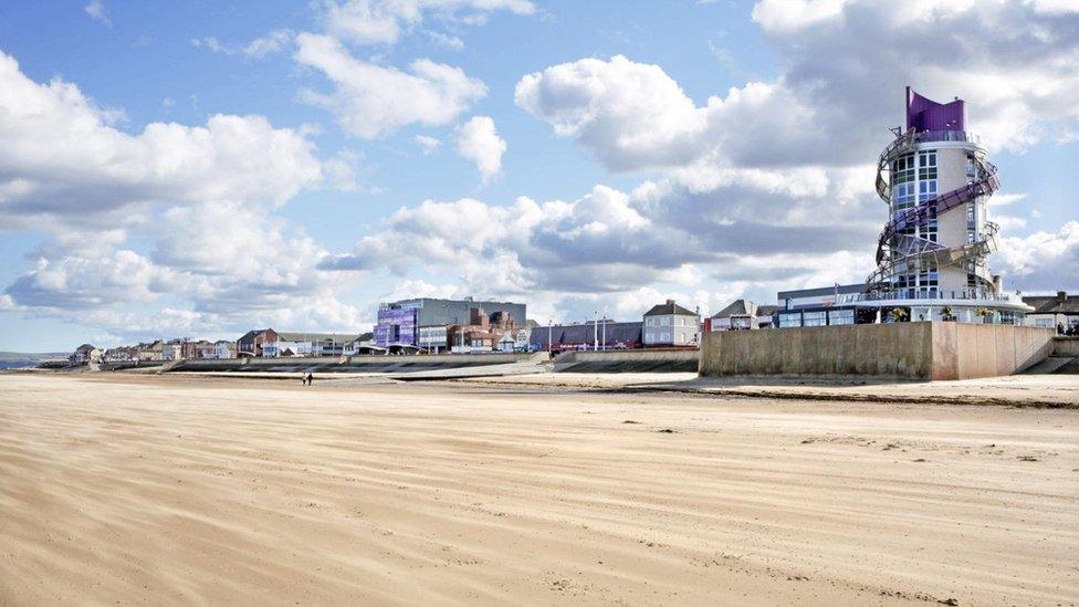 A tower and sea front buildings beside a beach