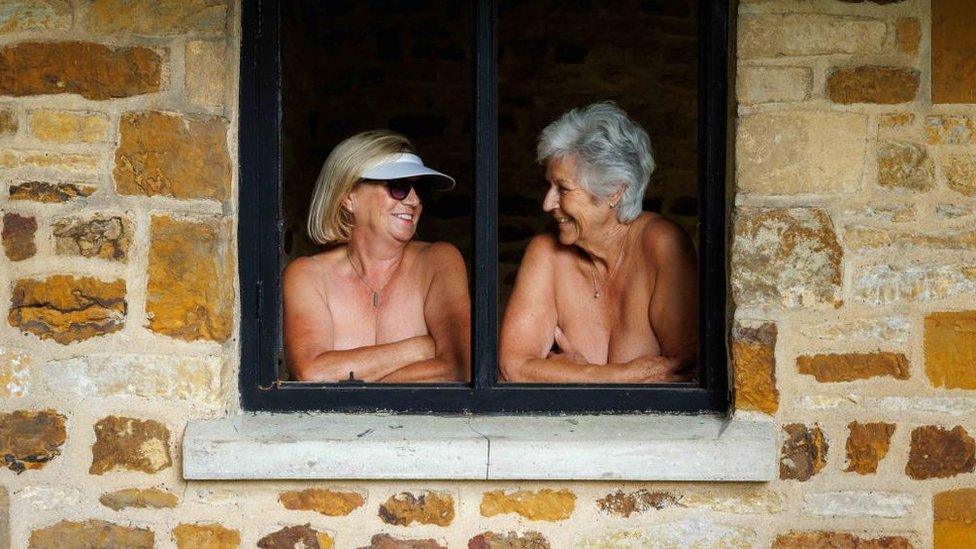 Two women in a window frame with arms folded strategically over their chests