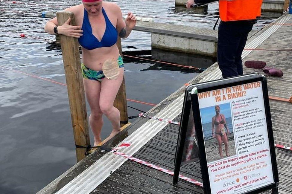 Gill climbs into a lake next to a sign explaining her story