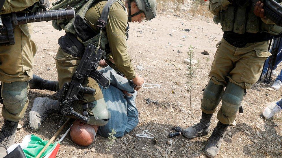 An Israeli soldier kneels on the head and neck of the Palestinian activist Khairi Hanoon at a protest in Shufa, in the occupied West Bank (1 September 2020)