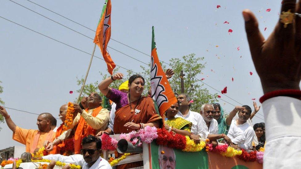 Uttar Pradesh Chief Minister Yogi Adityanath and Union Minister Smriti Irani wave at the crowd during a road show before filing her nomination papers on April 11, 2019 in Amethi, India.